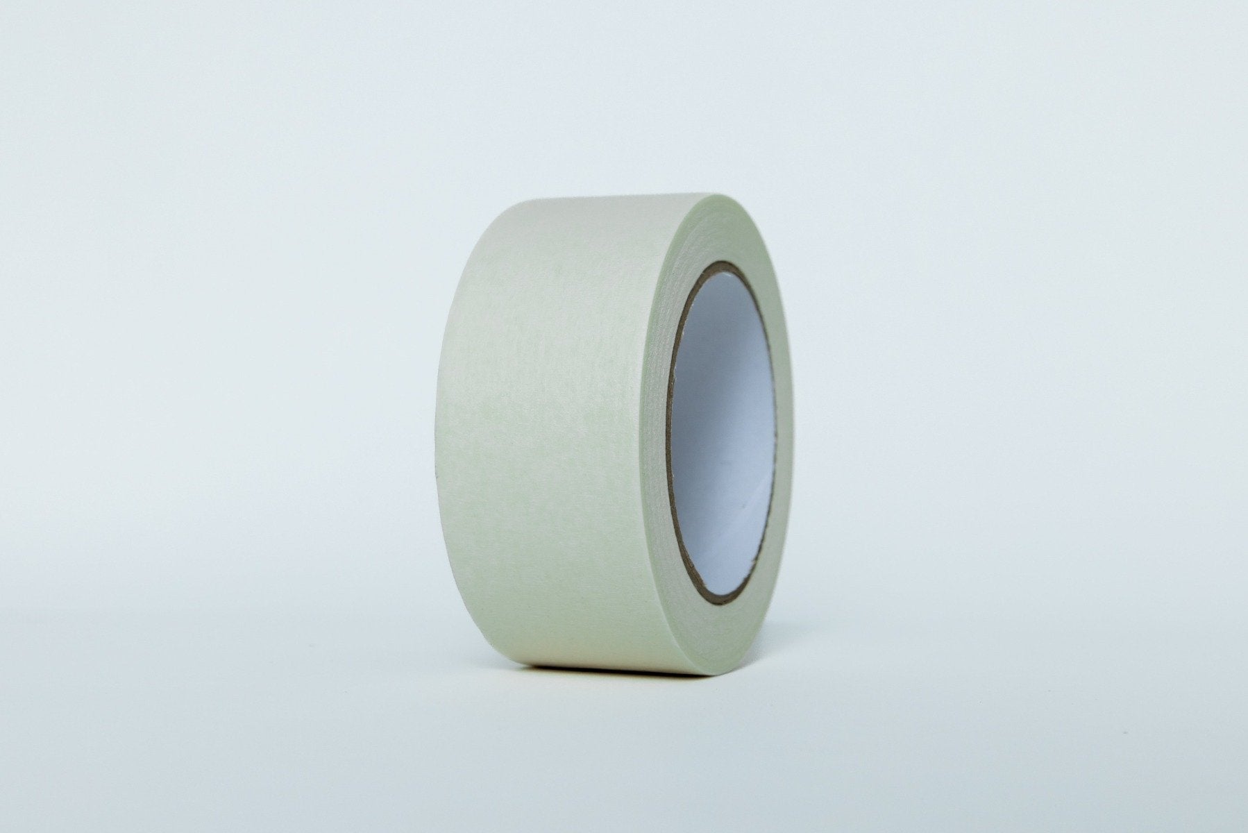 Roll of green painter's tape on a light gray background