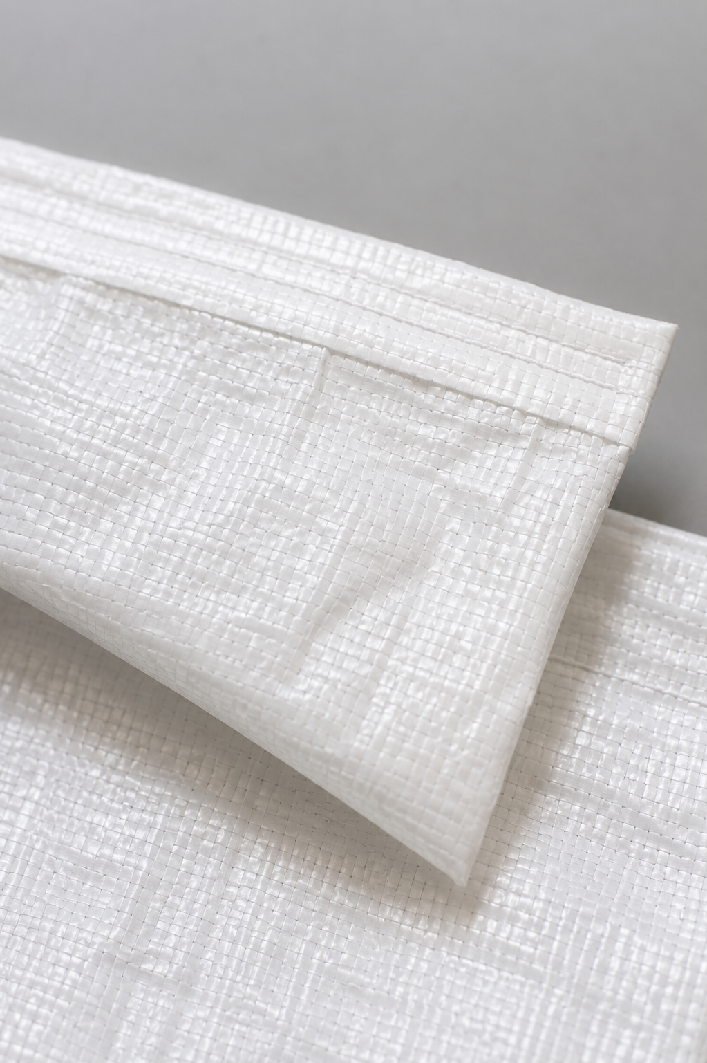 Close-up of woven polypropylene clothing export bag texture and stitching details