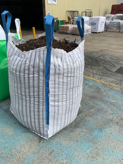 Large white bag filled with soil or compost on a concrete floor.
